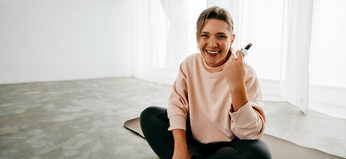 Young woman enjoying a snack after exercise on a yoga mat
