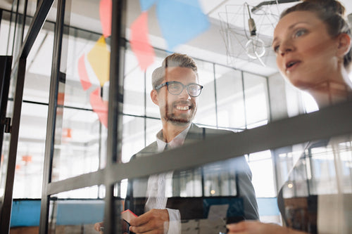 Coworkers discussing new ideas on a glass wall