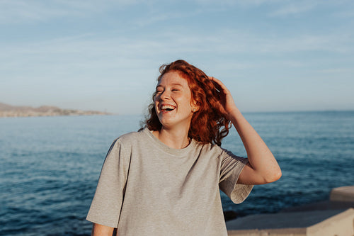 Happy young woman laughing cheerfully by the seaside