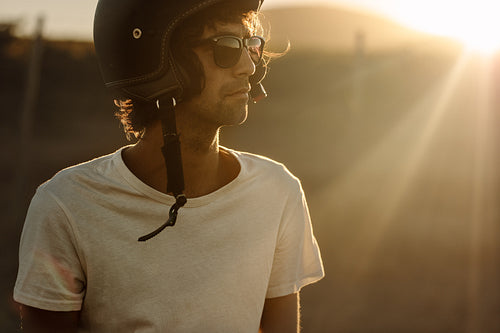 Biker in helmet and sunglasses standing outdoors