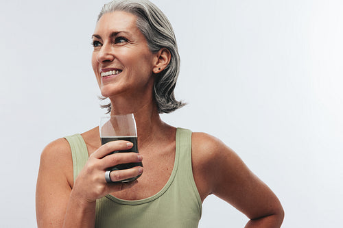 Woman sipping green superfood drink and wearing a smart ring in studio