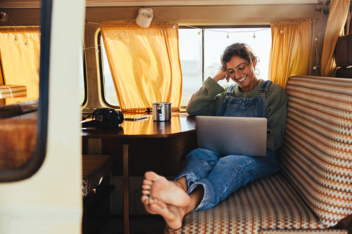 Relaxing while traveling: Woman with laptop in a cozy camper van