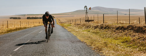 Racer riding a bicycle on the empty road in countryside
