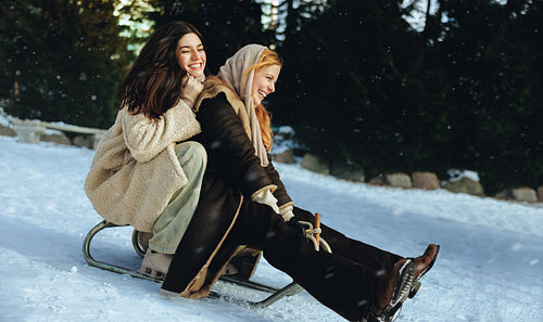 Women sledding together on a snowy hill