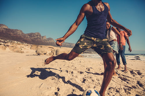 Friends playing football on the beach