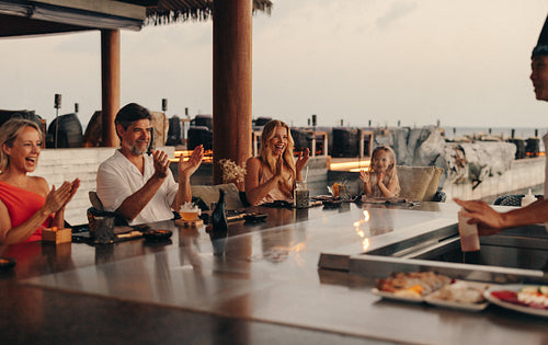 Family enjoying teppanyaki dining experience at a scenic seaside restaurant