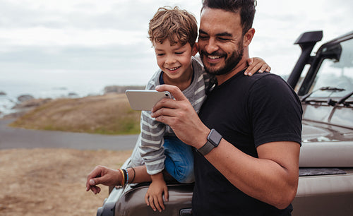 Father and son on road trip using smart phone