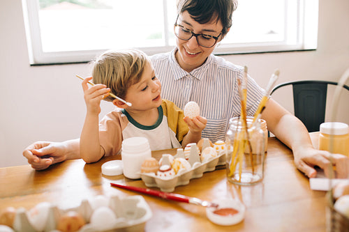 Boy painting eggs for easter with mom