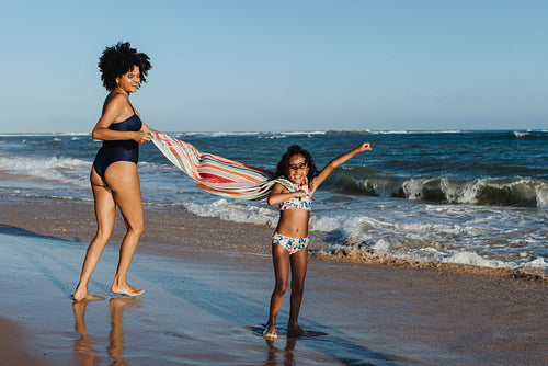 Mother and daughter having fun at the beach on a sunny vacation day
