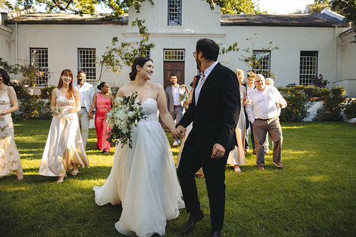 Bride and groom leading guests on a sunny outdoor wedding day