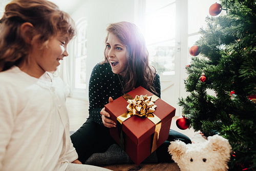 Mother presenting Christmas gift to daughter.