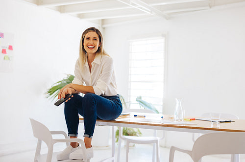 Creative businesswoman sitting on a conference table in an offic