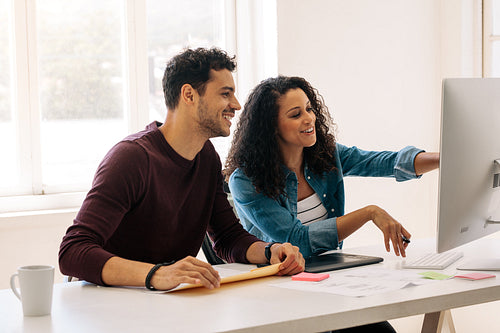 Business partners sitting together at the desk and discussing work in office