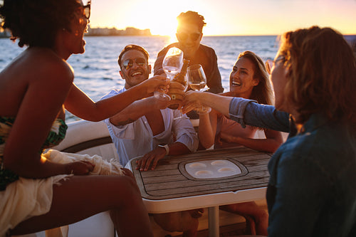 Group of friends having drinks at sunset boat party