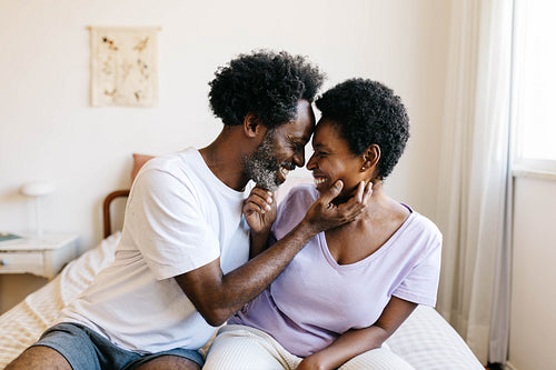 Black couple smiling at each other in romantic home moment