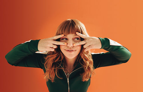 Woman making v signs with her hands in a studio