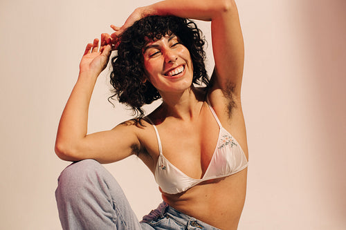 Unshaven young woman smiling cheerfully while wearing a bra