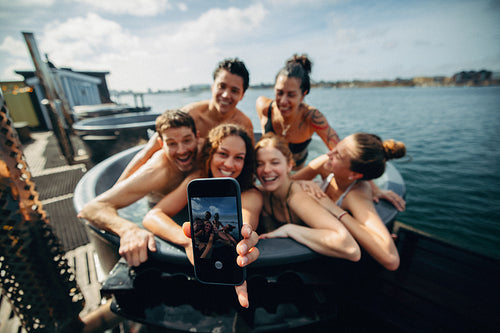 The friends enjoy a vacation getaway with a selfie in an outdoor hot tub.