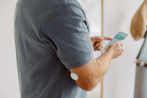 Senior monitors glucose sensor with smartphone at home