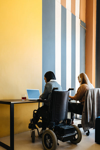 Two young women working together at a shared desk in an office