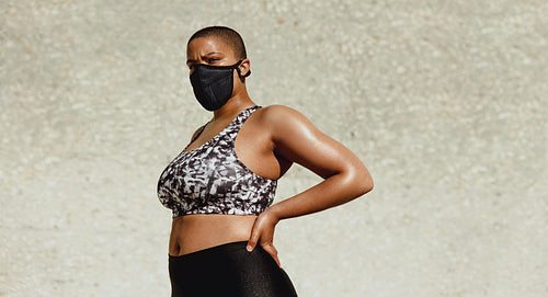 Androgynous woman with face mask taking break from workout