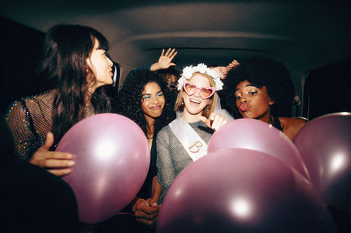 Group of friends celebrating with balloons in the back of a taxi