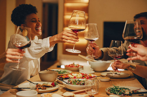 Friends toasting with wine during a cozy dinner at someone's home
