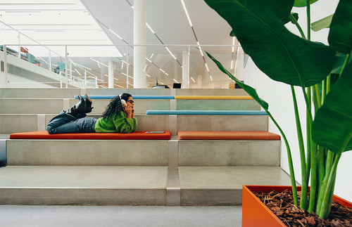 Study time finds the woman relaxing with a tablet in an indoor lounge