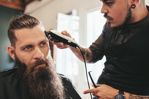 Young man getting trendy haircut at salon