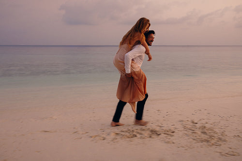 Young couple enjoying a luxury holiday at sunset on a romantic beach