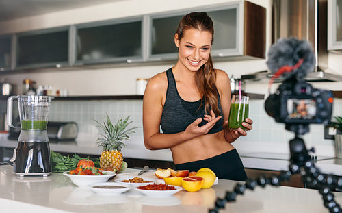 Young woman recording content for her video blog in kitchen.