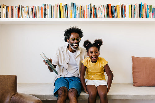 Mature dad and his daughter prepare to read together in a cozy living room