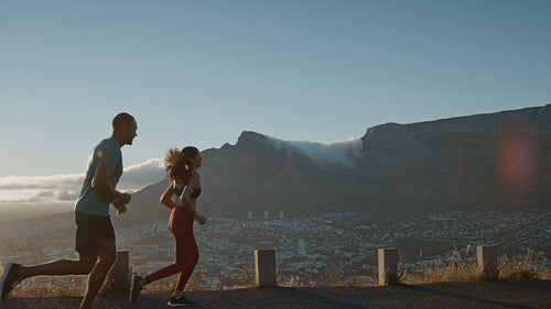 Two runners sprinting on a hillside road