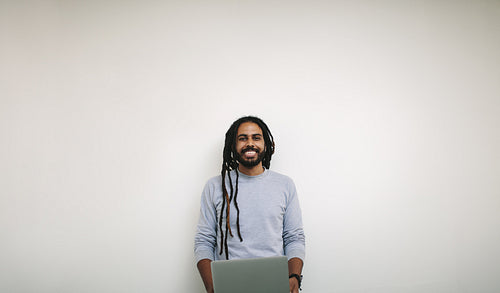 Portrait of a smiling businessman holding a laptop standing in office