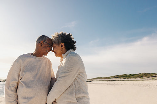Senior couple touching their heads together at the beach