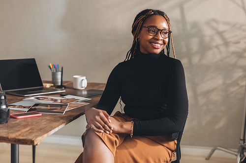 Contemplative young woman smiling in her home office