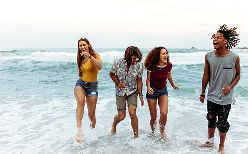 Cheerful young friends walking out of sea water