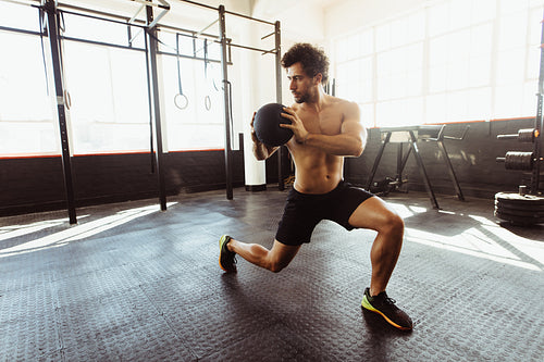 Muscular man exercising with medicine ball at gym