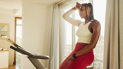 Young African American woman sweats it out on digital exercise bike