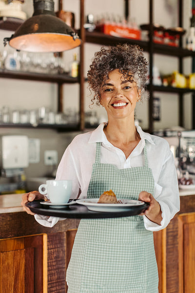 Carefree female barista holding a customer's order
