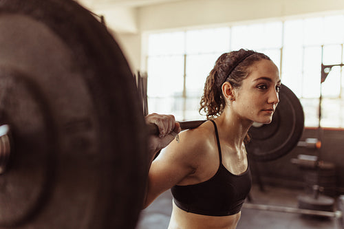 Healthy woman at gym exercising with barbell