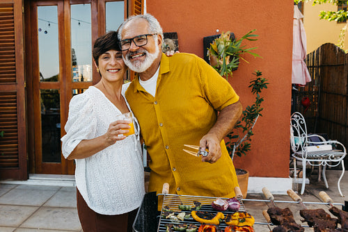 Senior couple enjoying a Brazilian churrasco at an outdoor family barbecue