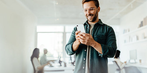 Business man reading a message on a mobile phone in an office