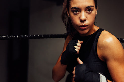 Athletic woman standing in a boxing ring with wrapped hands