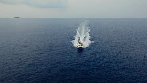 Boat speeds across the vast blue ocean leaving a foamy wake behind it