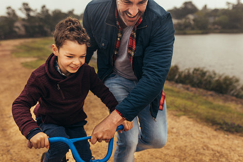 Father helping his son learn to ride a bicycle
