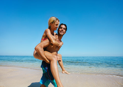 Couple enjoying piggybacking on the beach