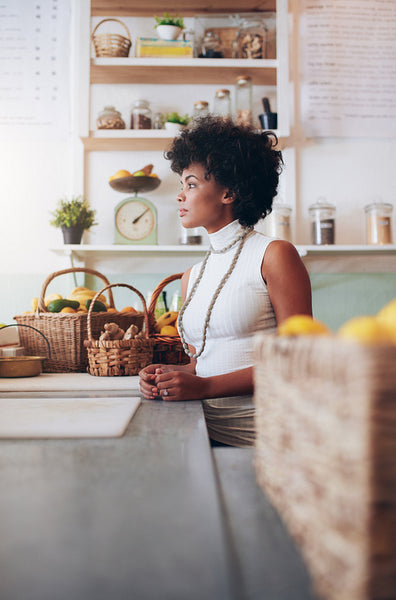 Young woman employee standing at juice bar counter