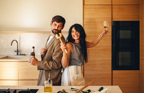 Joyful couple cooking and enjoying drinks in a modern kitchen