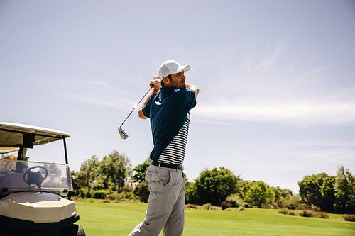 Male golfer swinging golf club with follow-through shot looking focused